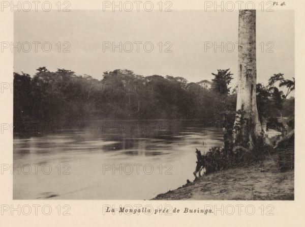 View of the Mongala near Businga, La Mongalla près de Businga, page, photomechanical print, number: 'Pl. 48.', photographer: Franz Thonner, Congo (country), cliché maker: Stengel & Markert, Dresden, 1896, Saxony, paper, collotype, photoprint, height 109 mm x width 162 mm, river, Mongala, A wide view of a calm river bordered by dense, dark treeline on the opposite bank and a sandy, vegetated shoreline in the foreground, with a tall pale tree trunk rising near the right edge and reflected ripples visible on the water surface.