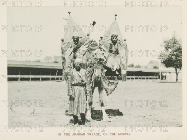 In the Arabian village, on the Midway, Three men with a camel at the World's Columbian Exposition in Chicago in 1893, page, photomechanical print, number: 'Plate 114', photographer: Charles Dudley Arnold, Chicago, photographer: HD Higinbotham, cliché maker: anonymous, 1893, Charles Dudley Arnold, HD Higinbotham, photographer, cliché maker, North America, Illinois, paper, collotype, photoprint, height 133 mm x width 190 mm, hoofed animals: camel, world fair, world exhibition, World's Columbian Exposition, A sepia-toned photograph showing a man standing in front of a camel that is heavily decorated with ornate fabrics and fringe, the camel carrying two seated men under pointed canopy-like coverings, the standing man wearing a striped robe and headwrap and holding a rope attached to the camel, a low fence and open ground behind them and a tree visible off to the right.