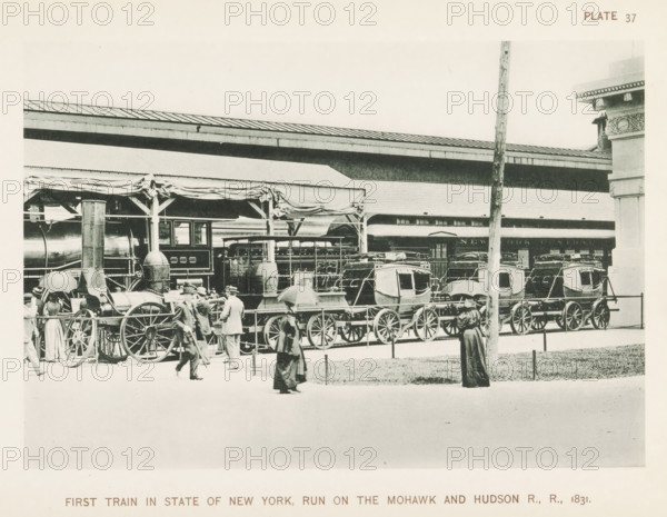 First train in State of New York, run On The Mohawk & Hudson R., R., 1831, First train to run on the Mohawk & Hudson Railroad, exhibited at the World's Columbian Exposition in Chicago in 1893, page, photomechanical print, number: 'Plate 37', photographer: Charles Dudley Arnold, Chicago, photographer: HD Higinbotham, clichémaker: anonymous, 1893, Charles Dudley Arnold, HD Higinbotham, photographer, clichémaker, North America, Illinois, paper, collotype, photoprint, height 131 mm x width 191 mm, railway, train, world fair, world exhibition, World's Columbian Exposition, A sepia-toned scene shows a train platform with a steam locomotive and a row of passenger carriages under a canopy with draped fabric, large spoked wheels visible beneath the vehicles, and a vertical pole in the foreground; several people in period clothing walk or stand nearby, some holding umbrellas, while architectural details of the station and decorative stonework appear at the right edge.