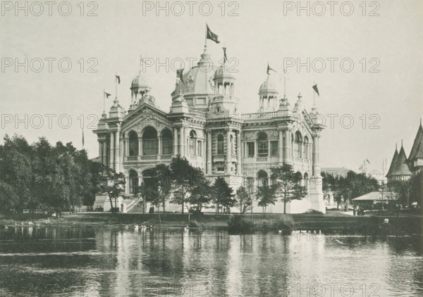 The Brazilian Building at the World's Columbian Exposition in Chicago in 1893, page, photomechanical print, number: 'Plate 74', photographer: Charles Dudley Arnold, Chicago, photographer: HD Higinbotham, cliché maker: anonymous, 1893, Charles Dudley Arnold, HD Higinbotham, photographer, cliché maker, North America, Illinois, paper, collotype, light printing, height 134 mm x width 190 mm, world fair, world exhibition, World's Columbian Exposition, A large ornate building with domes and towers stands behind a row of trees at the edge of a calm body of water, its reflection visible on the water surface; the façade shows arched windows, columns, decorative sculptures, and flags flying atop several roof elements, while small groups of people and a staircase appear near the building and a pavilion with pointed roofs is visible to the right.