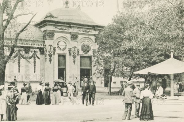 Government Building, Venezuela, Pavilion of Venezuela at the World's Columbian Exposition in Chicago in 1893, page, photomechanical print, number: 'Plate 76', photographer: Charles Dudley Arnold, Chicago, photographer: HD Higinbotham, cliché maker: anonymous, 1893, Charles Dudley Arnold, HD Higinbotham, photographer, cliché maker, North America, Illinois, paper, collotype, photoprint, height 133 mm x width 191 mm, world fair, world exhibition, World's Columbian Exposition, A sepia-toned scene shows an ornate building facade with decorative arches, columns, and a domed roof, flanked by trees; people in period clothing, including long skirts, hats, and suits, stand, walk, and gather in front of the entrance and on the steps, while a group near a canopy or umbrella appears to be conversing; architectural details include wreath motifs and sculpted ornaments above tall doorways, and foliage partially obscures the right side of the building.