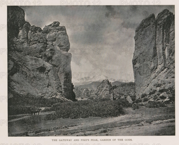 View of a rock pillar in Colorado Springs, Major Domo, Glen Eyrie, page, photomechanical print, Colorado Springs, cliché maker: New York Photo-Gravure Company, New York (city), c. 1888 - in or before 1893, photographer, North America, Colorado, paper, autotypie, height 135 mm x width 43 mm, rock-formations, A wide rocky landscape with two tall, steep rock formations framing an open valley, layered rock faces showing cracks and textures, lower rocky outcrops and scattered vegetation in the valley, distant snow-capped mountains visible through the gap, a cloudy sky above, and a dirt path in the foreground.