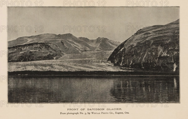 Front of Davidson Glacier, View of the Davidson Glacier, page, photomechanical print, inscription: 'From photograph No. 3, by Winter Photo Co., Eugene, Ore.', photographer: Winter Photo Co., Haines, cliché maker: Photo-Engraving Co., New York (city), c. 1885 - in or before 1890, North America, Alaska, paper, autotypie, height 95 mm x width 168 mm, glacier, Davidson Glacier, A grayscale image showing a wide body of calm water in the foreground reflecting ripples and darker vertical reflections, with a rocky shoreline rising behind it into layered hills and rugged slopes; the hills exhibit varied textures with lighter and darker patches and streaked surfaces, and a prominent steep, darker cliff appears on the right side.