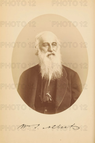 Wm. J. Albert, Portrait of William Julian Albert, photograph, page, photographer: Bendann Bros., c. 1866 - in or before 1871, paper, albumen print, height 148 mm x width 115 mm, Person, William Julian Albert, historical persons, A sepia-toned oval portrait of an older man with a long white beard and thinning hair, shown from the chest up and wearing a dark suit jacket over a vest and a narrow tie, his face turned slightly to one side with a neutral expression, set against a plain background within a light rectangular matte.
