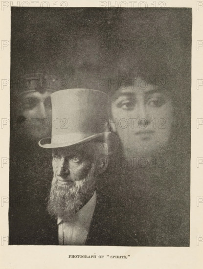 Photograph of 'Spirits', A man and two female spirits, page, photomechanical print, c. 1892 - in or before 1897, paper, autotype, height 145 mm x width 110 mm, adult man, materialization, appearance of spirit or ghost, A grainy black and white image shows a bearded man wearing a tall top hat and a suit, his face and upper body visible in the lower portion of the frame; above and behind him a translucent oversized face of a woman appears, with soft features and an expressionless gaze, and a faint secondary ghostly face is partially visible near the top left of the composition, all set against a dark textured background.