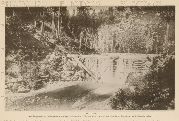 View of a dam on Slate Creek, California, Log Dam, page, photomechanical print, inscription: 'Upper Dam, Slate Creek', inscription: 'For impounding tailings from a hydraulic mine. The material behind the dam is tailings from a hydraulic mine.', c. 1885 - in or before 1890, North America, paper, collotype, photoprint, height 112 mm x width 183 mm, Print on second unnumbered page after page 132., dammed-up lake, A sepia-toned photograph showing a river flowing toward the foreground with a wooden log dam across it, reflected in the water; logs and beams are arranged horizontally and at angles on rocky riverbanks; steep forested hills rise on both sides with tall conifer trees and dense underbrush; rocks and scattered stones line the river edge; a lighter sandy or gravelly area is visible near the water; the overall scene is framed by a pale border.