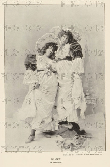 Study, page, photomechanical print, photographer: Hemperley, cliché maker: Hagopian Photo-Engraving Co., c. 1890 - in or before 1895, paper, autotype, height 159 mm x width 108 mm, adult woman, A sepia-toned photograph of two women standing close together wearing flowing light-colored dresses with floral embellishments and large ruffled sleeves, each holding up part of her skirt to reveal lace-trimmed underskirts and heeled shoes, both wearing wide brimmed hats decorated with flowers and looking slightly upward and to the side, one woman leaning her head toward the other, a draped fabric lying on the floor near their feet, and a plain mottled backdrop framed by a narrow border.