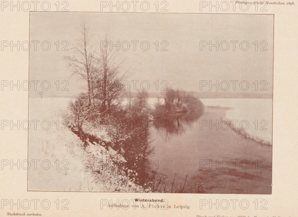 View of a landscape with snow, Winterabend, page, photomechanical print, inscription: 'Aufnahme von A. Fichte in Leipzig.', photographer: Albin Fichte, cliché maker: anonymous, printer (person): Wilhelm Knapp Verlag, Halle an der Saale, c. 1893 - in or before 1898, printer (person), Saxony-Anhalt, paper, autotypie, height 115 mm x width 156 mm, landscapes, snow, A sepia-toned photograph shows a snowy riverbank with bare trees and shrubs clustered near the water's edge, their branches reflected in the calm surface of the river, the opposite shore faintly visible through a hazy sky and snow-covered fields.