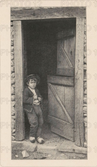 Boy in clogs in a doorway, page, photomechanical print, photographer: Paul Bourgeois, Paris, cliché maker: anonymous, printer (person): Wilhelm Knapp Verlag, c. 1893 - in or before 1898, printer (person), paper, autotypie, height 178 mm x width 89 mm, boy (child between toddler and youth), open door, wooden shoes, clogs, A sepia-toned photograph shows a young child standing in a wooden doorway of a rustic structure with stone-filled walls; the child wears a dark jacket over a lighter shirt, loose trousers, and simple shoes, and a hat sits on their head while they hold an object close to their chest with both hands; the partially open wooden door beside them has visible planks and diagonal bracing, and the door frame and surrounding stones show rough texture and weathering, with a stepped stone threshold and scattered small stones and debris on the ground outside.