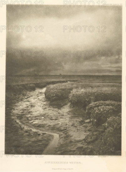 Aufziehendes Wetter, Landscape, with a ditch in the foreground, page, photomechanical print, photographer: Alfred Horsley Hinton, cliché maker: Meisenbach, Riffarth & Cie. (possibly), Berlin, publisher: Wilhelm Knapp Verlag, Halle an der Saale, 1897, 1897 - in or before 1901, printer (person), Saxony-Anhalt, paper, photoaquatint, height 199 mm x width 155 mm, behind semi-transparent cover with advertising message, landscapes, small canal, ditch, A monochrome image showing a marshy landscape with a winding water channel in the foreground leading toward a flat horizon, dense clumps of low vegetation flanking the channel, a wide expanse of cloudy sky occupying much of the upper area with darker clouds near the horizon, and a faint suggestion of distant shapes along the horizon line.