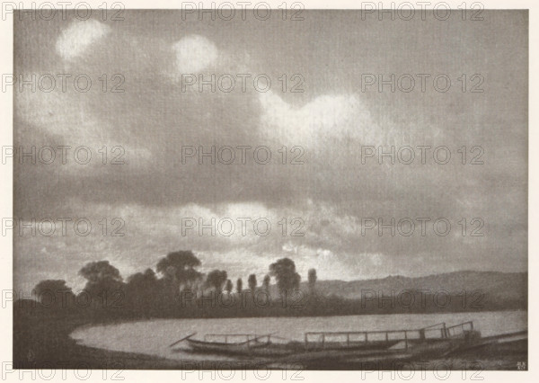 Landscape with jetty, page, photomechanical print, photographer: Otto Erhardt, cliché maker: Meisenbach, Riffarth & Cie. (possibly), Berlin, c. 1898 - in or before 1903, paper, autotypie, height 132 mm x width 190 mm, Print on second unnumbered page after page 206., landscapes, pier, quay, wharf, A grayscale landscape showing a body of water in the foreground with a curved shoreline, a small dock or platform extending over the water, and a few narrow boats moored nearby; behind the water a line of dark tree silhouettes rises against the sky, with taller slender trees interspersed among broader, rounded canopies; the sky occupies most of the image and is filled with soft, diffused clouds and lighter patches creating a textured, atmospheric backdrop.