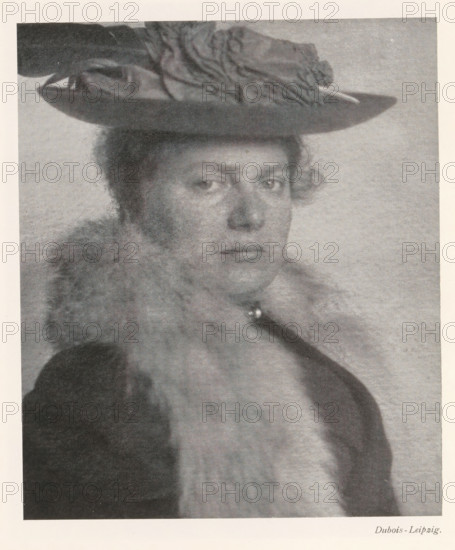 Portrait of an unknown woman, page, photomechanical print, photographer: Dubois, cliché maker: anonymous, c. 1898 - in or before 1903, paper, autotypie, height 167 mm x width 140 mm, Print on second unnumbered page after page 28., historical persons not known by name - BB - woman, A grayscale portrait of a person wearing a wide-brimmed hat with decorative fabric on top, showing a neutral facial expression and short curly hair at the temples, a fur or fluffy collar around the neck, and a dark coat or garment visible at the shoulders, all set against a plain light background.