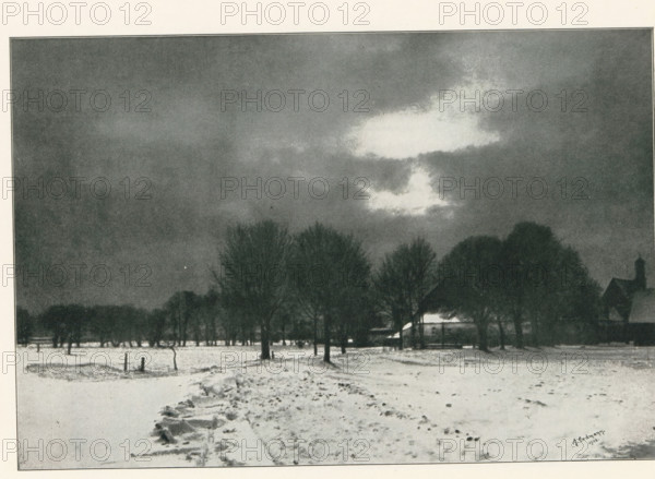 View of a farm in a winter landscape, page, photomechanical print, photographer: Alfred Erdmann, cliché maker: Meisenbach, Riffarth & Cie. (possibly), Berlin, 1902, 1902 - 1903, paper, autotypie, height 140 mm x width 207 mm, farm or solitary house in landscape, snow, A snowy landscape with a broad foreground of snow-covered ground and a rough path leading toward a line of tall leafless trees; behind the trees a low building with a sloped roof is partially visible and a taller structure with a pointed roof rises to one side; the sky above is dark and cloudy with a bright irregular cloud area near the center that contrasts with the surrounding darker clouds.
