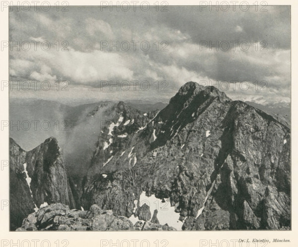 Mountain landscape, page, photomechanical print, photographer: LL Kleintjes, cliché maker: Meisenbach, Riffarth & Cie. (possibly), Berlin, c. 1898 - in or before 1903, paper, autotype, height 160 mm x width 201 mm, Print on fourth unnumbered page after page 290., mountains, A grayscale photographic image showing a rugged mountain range with steep, jagged peaks and rocky ridges, patches of snow nestled in crevices and on ledges, a distant layered horizon of softer mountains fading into the background, and a sky filled with textured clouds stretching across the upper portion of the scene.