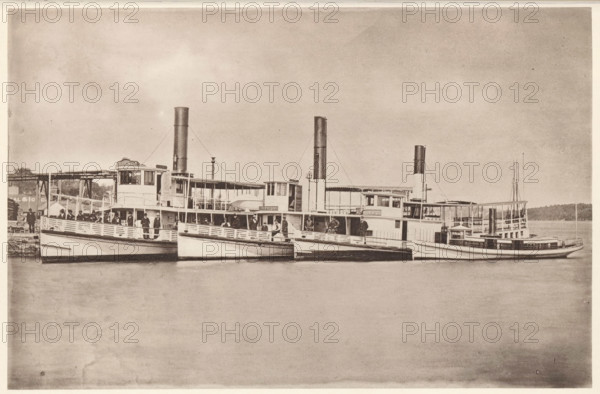 Sebenoa, Sasanoa, Samoset, Creedmoor, Eastern Steamboat Company's Bath and Boothbay Line, View of the Sebenoa, Sasanoa and Samoset and Creedmoor ferries near Bath and Boothbay, Maine, page, photomechanical print, c. 1875 - in or before 1880, North America, paper, collotype, photoprint, height 120 mm x width 184 mm, Print on second unnumbered page after page 24., ferry, A sepia-toned photograph showing a row of passenger steamships moored side by side at a dock, each vessel featuring tall smokestacks, covered upper decks, and open railings. People stand and sit along the decks and near the railings, some clustered under canopies and others near the wheelhouses. The water in front of the boats is calm and reflects parts of the hulls. In the background a low treeline and parts of the dock structure are visible. The sky above is wide and lightly textured.