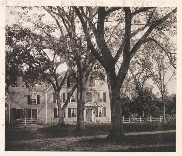 View of the home of Oliver Wendell Holmes Sr. in Cambridge, page, photomechanical print, photographer: William James Stillman, Cambridge (MA), cliché maker: anonymous, United States of America, c. 1866 - in or before 1876, North America, Massachusetts, paper, collotype, photoprint, height 148 mm x width 175 mm, Print opposite frontispiece., housing, façade (of house or building), A front view of a two-story house partially obscured by large trees with thick trunks and spreading branches, the house has multiple windows with shutters and a visible doorway with a small pediment, a wooden fence runs along the front yard, dense foliage and tree canopies fill the upper portion of the image, and the foreground shows a shaded grassy area and a dirt path.