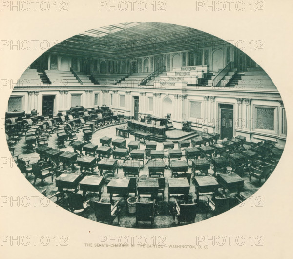 Interior of the senate chamber in the Capitol in Washington DC, The senate chamber in the Capitol - Washington, DC, page, photomechanical print, Capitol (Washington DC), c. 1883 - in or before 1893, North America, Washington DC, District of Columbia, paper, collotype, photoprint, height 148 mm x width 201 mm, Upper House, Senate, national government, An oval-framed photograph of an ornate semicircular chamber with rows of wooden desks and chairs arranged in a curved formation facing a raised central dais, carved decorative paneling and fluted pilasters along the walls, an elaborately coffered ceiling, tiered gallery seating with staircases, a central lectern and benches on the dais, upholstered chairs against the walls, patterned wall panels, and various small tables and wastebaskets scattered among the desks.