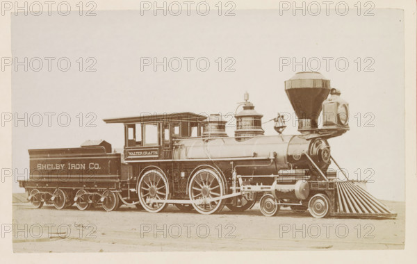 American passenger steam locomotive, photograph, page, United States of America, c. 1871 - in or before 1881, photographer, North America, paper, albumen print, height 122 mm x width 200 mm, Photo on page 62., steam locomotive, A sepia-toned photograph of a steam locomotive and its tender occupying the lower portion of the image, showing a large cylindrical boiler with domed fittings, a tall conical smokestack with a flared top, a rectangular headlamp mounted at the front, and a decorative cowcatcher on the leading end; the cab has open window bays and a roof with overhang, and the tender behind the cab is boxy with side panels; the train rests on visible spoked driving wheels and smaller leading wheels with connecting rods and exposed mechanical linkages; surface details include rivets, piping, trim panels, and painted signage areas on the tender and cab; the background is a light, empty expanse with no other objects or people visible.
