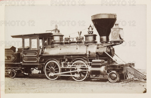 American steam locomotive, photograph, page, number: '39', United States of America, c. 1871 - in or before 1881, photographer, North America, paper, albumen print, height 124 mm x width 200 mm, Photo on page 123., steam locomotive, A sepia-toned photograph shows the side view of a vintage steam locomotive with a cab, boiler, large driving wheels, and a tall conical smokestack, with visible piping, valves, domes, and a large headlamp housing at the front; ornate paneling and decorative trim appear on the cab and tender, and a metal cowcatcher extends from the front toward the ground, while the locomotive rests on rails set in a dirt surface.