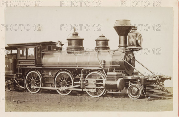 American freight steam locomotive, photograph, page, number: '844', United States of America, c. 1871 - in or before 1881, photographer, North America, paper, albumen print, height 124 mm x width 198 mm, Photo on page 96., steam locomotive, A sepia-toned photograph of a vintage steam locomotive showing the side of the engine and part of the tender, with large spoked driving wheels and a visible cowcatcher at the front. The cylindrical boiler runs along the center with domed steam domes on top and a tall conical smokestack near the front. The cab has open windowed panels and a roof extending over the rear of the boiler. Brass fittings, pipes, and valves run along the boiler and frame, and a rectangular lantern with a round glass face is mounted at the front. Various mechanical linkages and rods connect the wheels, and there is a cylindrical tank and other rounded components attached near the pilot. The ground beneath the locomotive is bare and slightly uneven.