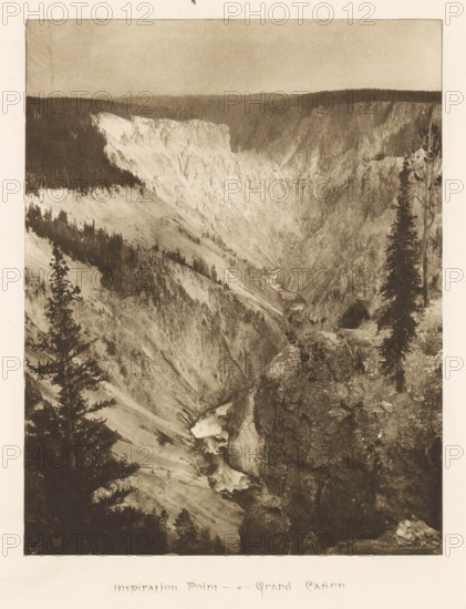 Inspiration point - Grand Cañon, page, photomechanical print, photographer: Frank Jay Haynes, Yellowstone National Park, cliché maker: The Photo-gravure Co., New York (city), c. 1882 - in or before 1887, North America, paper, photoaquatint, height 214 mm x width 166 mm, ravine, chasm, abyss, canyon, Grand Canyon (Yellowstone National Park), A sepia-toned photograph of a deep rocky canyon with steep light-colored cliffs and darker forested rimlines, a winding river flowing through the canyon with visible cascades and white water, rugged foreground rocks and a narrow ledge with sparse vegetation, several tall conifer trees framing the scene on the left and right, distant hazy hills forming the horizon under a muted sky.