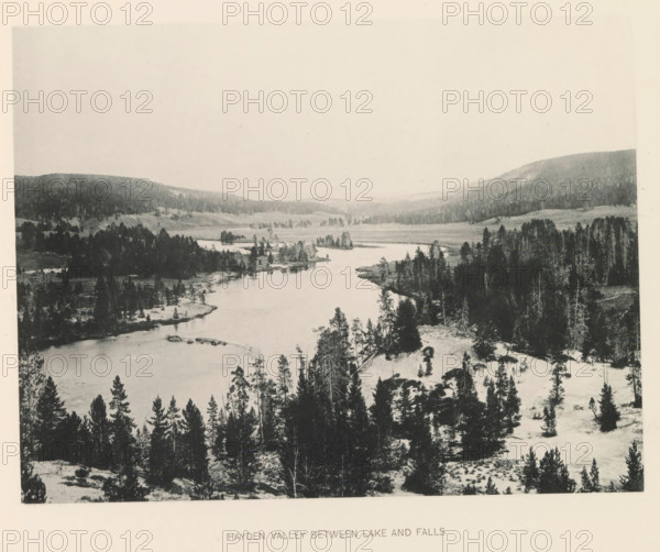 Hayden Valley between lake and falls, page, photomechanical print, photographer: Frank Jay Haynes, Yellowstone National Park, cliché maker: The Photo-gravure Co., New York (city), c. 1886 - in or before 1891, North America, paper, collotype, photoprint, height 165 mm x width 212 mm, dale, valley, Hayden Valley, A wide river winds through a valley flanked by forested hills, with clusters of evergreen trees along the riverbanks and on rocky, snow-dusted ground, the water reflecting pale tones and narrowing toward the distant horizon where low ridges and tree-covered slopes fade into a light sky.