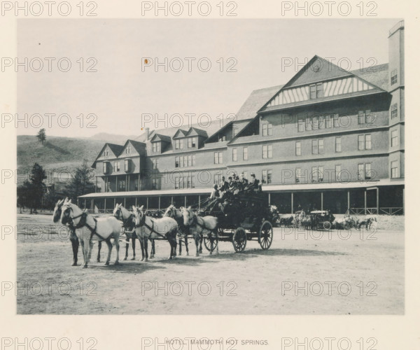Hotel mammoth hot springs, page, photomechanical print, photographer: Frank Jay Haynes, Yellowstone National Park, cliché maker: The Photo-gravure Co., New York (city), c. 1886 - in or before 1891, North America, paper, collotype, photoprint, height 164 mm x width 216 mm, hotel, hostelry, inn, four-wheeled, animal-drawn vehicle, eg: cab, carriage, coach, façade (of house or building), A large multi-story wooden hotel with a long covered porch and multiple dormer windows fills the right and center of the scene, with a hillside and scattered trees visible behind it on the left; in front of the building a team of horses harnessed to a wagon stands in the foreground, several people seated on the wagon and others nearby, additional carriages and horses lined up along the porch, and the ground in front appearing as an open dirt area.