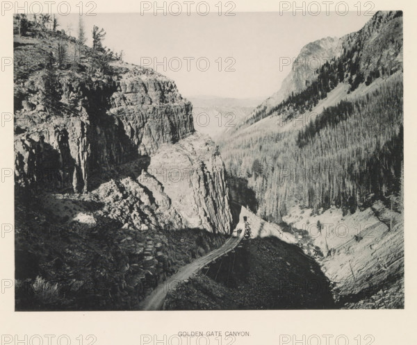 Golden Gate Canyon, page, photomechanical print, photographer: Frank Jay Haynes, Yellowstone National Park, cliché maker: The Photo-gravure Co., New York (city), c. 1886 - in or before 1891, North America, paper, collotype, photoprint, height 165 mm x width 215 mm, ravine, chasm, abyss, canyon, A black and white image showing a rugged canyon with steep rock cliffs on one side and a densely forested slope on the other, a narrow winding road or wooden trestle running along the canyon edge, sparse trees and shrubs on the rocky ledges, and distant layered hills visible through the canyon opening.
