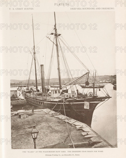 View of the George S. Blake in the navy yard in Washington DC, page, photomechanical print, inscription: 'The 'Blake' at the Washington navy yard. The dredging gear ready for work.', name: 'Heliotype Printing Co., 220 Devonshire St., Boston.', number: 'Plate 24.', United States of America, printer (person): Heliotype Printing Company, Boston (Massachusetts), c. 1870 - in or before 1880, printer (person), North America, Massachusetts, paper, collotype, photoprint, height 210 mm x width 164 mm, steamship, motorship, Washington DC, District of Columbia, A sepia-toned photograph of a docked sailing vessel seen from an elevated quay, showing the ship's bow and side with ornate carvings, rigging, tall masts, and spars, along with coiled ropes and chains on the deck and pier; a steam funnel rises amidships and various deck machinery and pulleys are visible, while the foreground shows a stone-edged quay with scattered planks, ropes, and a gas lamp post; water surrounds the vessel and a distant...