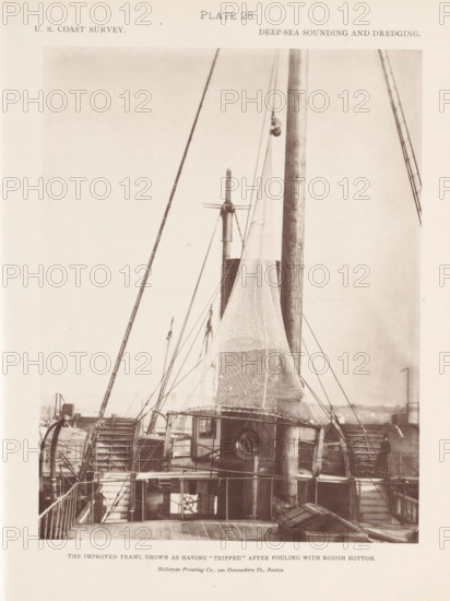 View of a trawl on the deck of the George S. Blake, page, photomechanical print, number: 'Plate 28.', inscription: 'The improved trawl shown as having 'tripped' after fouling with rough bottom.', name: 'Heliotype Printing Co., 220 Devonshire St., Boston.', United States of America, printer (person): Heliotype Printing Company, Boston (Massachusetts), c. 1870 - in or before 1880, printer (person), North America, Massachusetts, paper, collotype, photoprint, height 208 mm x width 160 mm, fishing net, ships (in general), A sepia-toned photograph showing the deck and upper structures of a vessel with tall masts, rigging lines, and large nets suspended from the masts; paddle wheels are visible on both sides of the vessel amid stairways and railings, with a cabin structure near the center featuring a round porthole and steps leading down to lower decks; wooden deck planks, coiled ropes, and various winches and pulleys are visible, and a person stands near one of the paddle wheels on the right...