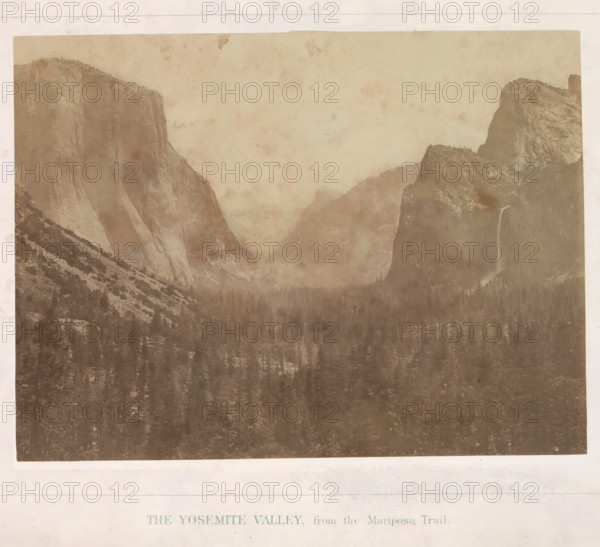The Yosemite Valley, from the Mariposa Trail, View of the Yosemite Valley, photograph, page, number: 'I.', photographer: Carleton E. Watkins, Yosemite Valley, c. 1860 - in or before 1868, North America, California, paper, albumen print, height 155 mm x width 205 mm, mountains, dale, valley, A sepia-toned landscape photograph showing a wide valley framed by steep rock cliffs and rounded granite formations, with a dense forest of coniferous trees filling the valley floor. One tall cliff on the left rises nearly vertically with striated rock faces and a sloping base, while opposite on the right there are layered rocky outcrops and a narrow waterfall cascading down a dark rock face. Mist or low clouds hang between the distant ridges, softening the outlines of the mountains, and the image has a faded, aged appearance with light mottling and uneven tonality across the sky and rock surfaces.