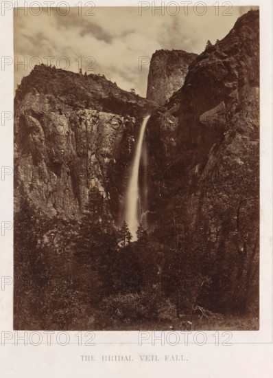 View of Bridalveil Falls in Yosemite Valley, The Bridal Veil Fall, photograph, page, number: 'II.', photographer: Carleton E. Watkins, Yosemite Valley, c. 1860 - in or before 1868, North America, California, paper, albumen print, height 204 mm x width 155 mm, waterfall, mountains, dale, valley, Bridalveilwaterval, A tall, narrow waterfall cascades down a steep rock face between rugged cliffs, the water appearing smooth and slightly blurred as it falls into a darker, wooded area below; surrounding the waterfall are high, jagged rock formations with visible striations and scattered trees along the ridgelines, and above them a cloudy sky with soft, diffuse light.