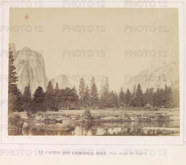 El Capitan and Cathedral Rock, View down the Valley, photograph, page, number: 'IV.', photographer: Carleton E. Watkins, Yosemite Valley, c. 1860 - in or before 1868, North America, California, paper, albumen print, height 156 mm x width 208 mm, mountains, rock-formations, dale, valley, El Capitan, A sepia-toned landscape photograph showing a wide valley with a reflective river in the foreground, a grassy riverbank and scattered bushes along the shore, a dense stand of tall conifer trees rising behind the river, large sheer granite cliffs and domed rock faces framing both sides of the scene, and a pale sky above.