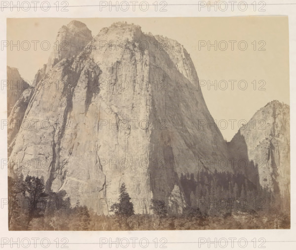 Cathedral Rock, near view from the front, View of the Middle Cathedral Rock in the Yosemite Valley, photograph, page, number: 'V.', photographer: Carleton E. Watkins, Yosemite Valley, c. 1860 - in or before 1868, North America, California, paper, albumen print, height 156 mm x width 206 mm, mountains, rock-formations, dale, valley, A sepia-toned photograph showing a steep, sheer rock face rising from a forested base, with rugged vertical cracks and ledges, lighter rock surfaces on sunlit faces and darker shaded areas creating depth, a few scattered trees and shrubs clinging near the top and along narrow terraces, a smaller rocky peak visible to the right, and a band of trees and vegetation at the bottom edge.