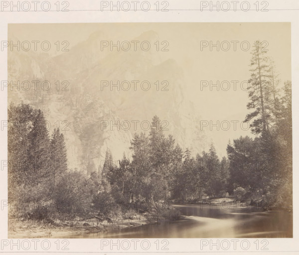 The Three Brothers, View of the Three Brothers mountain formation in the Yosemite Valley, photograph, page, number: 'VIII.', photographer: Carleton E. Watkins, Yosemite Valley, c. 1860 - in or before 1868, North America, California, paper, albumen print, height 155 mm x width 205 mm, mountains, rock-formations, dale, valley, Three Brothers, A sepia-toned landscape photograph showing a river in the foreground with smooth reflective water, a sandy or rocky shoreline, dense stands of trees and shrubs along the banks, taller coniferous trees rising above the treeline, and distant steep rocky cliffs and mountain faces fading into a pale sky.