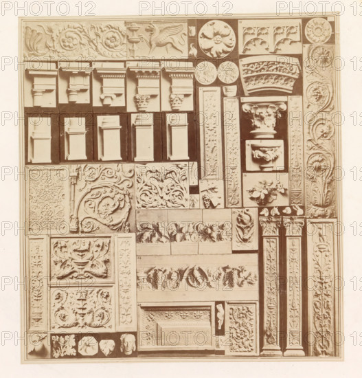 Casts of ancient building fragments, photograph, page, photographer: HG Smith, photographer: HW Tupper, c. 1864 - in or before 1874, paper, albumen print, height 184 mm x width 170 mm, column, pillar, architecture, architectural detail, stylistic and formal differentiation of art, A rectangular panel filled with numerous carved plaster or stone relief fragments arranged in a grid, showing a variety of architectural elements and ornamental motifs in a uniform pale tone; there are sections depicting capital tops, column shafts, floral rosettes, scrolling acanthus leaves, grape clusters, stylized vines, circular medallions, rectangular plaques with intricate arabesque and foliate patterns, projecting cornice and molding profiles, small sculpted heads and figurative fragments, and narrow vertical pilaster-like strips with repeating leaf and flower carvings, all photographed against a darker background that highlights the raised details.