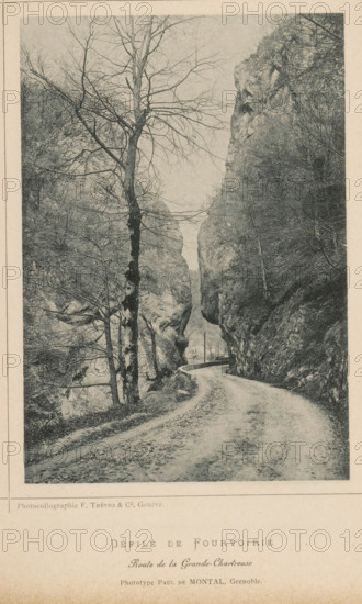 Défilé de fourvoirie - Route de la Frande-Charteuse, View of a path through an area of rocks, page, photomechanical print, inscription: 'Revue de Photographie', maker: MP du Montal, maker: F. Thévoz & Cie., c. 1887 - in or before 1892, paper, collotype, photoprint, height 154 mm x width 110 mm, road, path, rocks, A narrow winding dirt road runs between tall rock cliffs, curving away toward a distant opening; bare deciduous trees with thin branches line the roadside and stand against the rocky faces, one prominent tree trunk close to the foreground showing textured bark; steep rock walls rise on both sides with rough surfaces and scattered vegetation, and a low stone or concrete barrier edges part of the road near the cliff; the scene is monochrome and framed by a pale border.