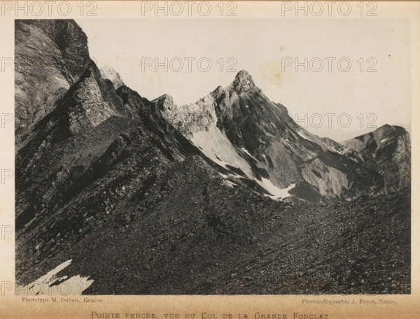 View of the Col de la Forclaz, Pointe percée, vue du Col de la Grande Forclaz, page, photomechanical print, maker: Marcel Dubois, maker: Jules Royer, c. 1892 - in or before 1897, paper, collotype, photoprint, height 120 mm x width 172 mm, mountains, Col de la Forclaz, A wide black-and-white photograph of a rugged mountain scene showing steep rocky ridges and jagged peaks against a pale sky, with areas of lighter scree and patches of snow on the slopes, a prominent pointed summit near the center, and textured rocky foreground leading up to the base of the mountains.