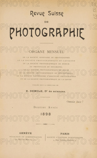 Revue suisse de photographie, Société genevoise de photographie, et al., book, annotation: 'NOV, 1994', number: 'bl. 112, 143', name: 'Jer. Van Severen, Ruysselede', collector's mark: 'Dr. Frans de Vos, 54, Ter Rivierenlaan, DEURNE, Telst.: 5.6.90 - Postcheckr. 504.1..', editor (person who revises): Eugène Demole, 1898, Eugène Demole, editor (person who revises), textile materials, pasteboard, biological material, paper, linen (material), leather, printing, shell marbled paper, agate marbled paper, lithography, autotype, collotype, height 231 mm x width 163 mm x thickness 28 mm, A vertical page with aged beige paper showing large bold stylized lettering near the top, a centered thin horizontal rule below it, and multiple lines of smaller printed lines arranged in centered blocks down the page, with a decorative divider element in the lower-middle area and two wider columns of text near the bottom separated by a thin vertical line, plus small pencil scribbles in the top right margin.