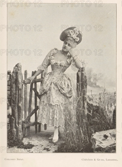 Portrait of an unknown woman at a fence, page, photomechanical print, inscription: 'Phot. Corresp.', inscription: 'Concours Suter.', monogram: 'AG ph.', maker: Châtelain & Gross, cliché maker: unknown, c. 1894 - in or before 1899, paper, autotypie, height 143 mm x width 104 mm, historical persons not known by name - BB - woman, gate, entrance, A sepia-toned photograph of a woman standing by a rustic wooden gate and fence, wearing an ornate dress with lace and floral trim and a wide skirt with gathered overskirt, a hat decorated with flowers, gloves, a choker necklace, and a bracelet; she leans with one elbow on a fence post and rests her hand against her cheek while the other hand holds the gate, grasses and rough stones surround the fence, and the background is a plain sky.