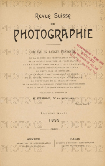 Revue suisse de photographie, Société genevoise de photographie, et al., book, collector's mark: 'Dr. Frans de Vos, 54, Ter Rivierenlaan, DEURNE, Telst.: 5.6.90 - Postcheckr. .04.1..', annotation: 'NOV, 1994', annotation: 'appareils à main. Page 45.', name: 'Jer. Van Severen, Ruysselede', editor (person who revises): Eugène Demole, 1899, Eugène Demole, editor (person who revises), textile materials, pasteboard, biological material, paper, linen (material), leather, printing, shell marbled paper, agate marbled paper, lithography, autotype, collotype, height 234 mm x width 168 mm x thickness 27 mm, The image shows an aged, beige paper cover with a large stylized title near the top and multiple lines of printed text arranged vertically down the center; there is a diagonal stamped mark in a darker color on the right side of the page and a small decorative flourish near the middle; the paper has a slightly textured, worn appearance and even margins around the printed content.