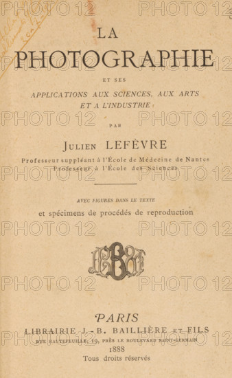 La photographie et ses applications aux sciences, aux arts et à l'industrie, book, annotation: 'June 1999, ... April 1993', annotation: '..., ..., 20-7-1915', writer (clerical worker): Julien Lefèvre, publisher: JB Baillière et Fils, Paris, in or before 1888, Julien Lefèvre, JB Baillière et Fils, writer (clerical worker), publisher, pasteboard, biological material, leather, paper, printing, height 197 mm x width 136 mm x thickness 31 mm, The image shows an aged book title page printed on beige, textured paper with a large heading centered near the top and several lines of smaller printed text beneath it; there is a decorative monogram-like emblem midway down the page, a horizontal rule above a short line of small italicized text, and a faint diagonal handwritten mark near the upper left corner; the printing uses serif fonts in varying sizes and weights and the page exhibits subtle age spots and discoloration.