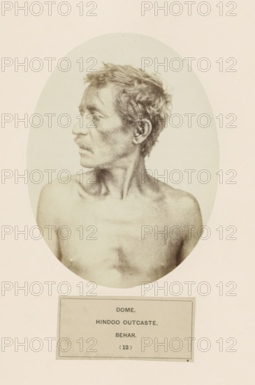 Portrait of an unknown man from the Dom community of Bihar in eastern India, photograph, page, inscription: 'DOME., HINDOO OUTCASTE., BEHAR.', number: '(12)', Bihar, c. 1858 - in or before 1868, photographer, North India, paper, albumen print, height 159 mm x width 120 mm, human races, peoples, nationalities, A sepia-toned oval portrait of a shirtless man shown from the shoulders up, facing left in profile, with short tousled hair, a thin mustache, defined collarbones, and a lean neck, set against a pale background and mounted above a rectangular plaque.