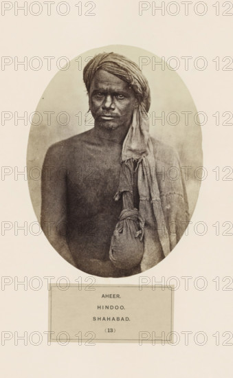 Portrait of an unknown man from the Ahir community of Arrah (former Shahabad) in Bihar, India, photograph, page, inscription: 'AHEER., HINDOO., SHAHABAD.', number: '(13)', Bihar, c. 1858 - in or before 1868, photographer, North India, paper, albumen print, height 160 mm x width 120 mm, human races, peoples, nationalities, An oval-framed sepia portrait of a bare-chested man wearing a wrapped headscarf and a draped cloth over one shoulder, with a tied pouch hanging from the draped cloth; the man's face has a neutral expression and his gaze is directed forward.
