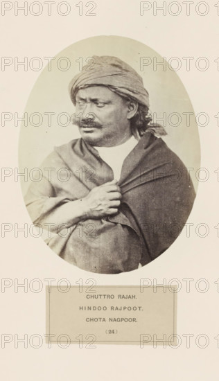 Portrait of the Maharaja of Chota Nagpur, photograph, page, number: '(24)', inscription: 'CHUTTRO RAJAH., HINDOO RAJPOOT., CHOTA NAGPOOR.', photographer: Benjamin Simpson (possibly), Chota Nagpur, c. 1858 - in or before 1868, Jharkhand, paper, albumen print, height 158 mm x width 120 mm, head-gear: turban, human races, peoples, nationalities, A sepia-toned oval portrait of a man shown from the waist up wearing a wrapped headscarf and a draped shawl, looking slightly to his left with a mustache and short beard, one hand gripping the shawl at his chest, set against a plain light background with a rectangular label area below the portrait.