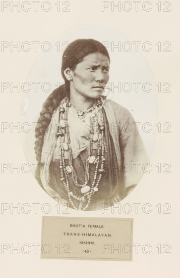 Portrait of an unknown woman from the Bhutia community of Sikkim, photograph, page, inscription: 'BHOTIA FEMALE., TRANS-HIMALAYAN., SIKHIM.', number: '(45)', photographer: Benjamin Simpson (possibly), Sikkim, c. 1858 - in or before 1868, paper, albumen print, height 175 mm x width 129 mm, human races, peoples, nationalities, A portrait of a woman shown from the chest upward inside an oval frame, with dark hair braided over one shoulder and a solemn facial expression; she wears layered clothing and multiple long beaded necklaces with large and small beads, and a circular earring visible on one ear.