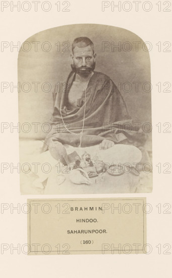 Portrait of an unknown brahmin (Hindu priest) with items for his morning prayers, from Saharanpur, Uttar Pradesh, India, photograph, page, inscription: 'BRAHMIN., HINDOO., SAHARUNPOOR.', number: '(160)', Saharanpur, c. 1858 - in or before 1868, photographer, North India, paper, albumen print, height 123 mm x width 95 mm, human races, peoples, nationalities, ritual practices with particular objectives, Hinduism, Buddhism, Jainism, A sepia-toned photograph shows a seated man with short hair and a full beard wearing draped cloth over his shoulders and body, a thin cord hanging around his neck, his hands resting on his knees; in front of him are various ritual objects including a conch shell, small bowls, a plate with items arranged on it, and a shallow dish, all placed on a cloth surface, with a plain backdrop and rounded top framing the image.