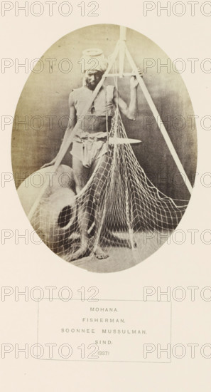 Potrait of an unknown fisherman from the Mohana tribe with a net and a stone vessel, Sindh, Pakistan, photograph, page, inscription: 'MOHANA., FISHERMAN., SOONNEE MUSSULMAN., SIND.', number: '(337)', photographer: Henry Charles Baskerville Tanner (possibly), photographer: William Robert Houghton (possibly), c. 1862 - in or before 1872, paper, albumen print, height 145 mm x width 109 mm, fisherman, human races, peoples, nationalities, A sepia-toned oval photograph shows a barefoot man standing behind and among fishing equipment; he wears a wrapped cloth around his head and minimal cloth garments around his torso and waist, with a sash tied at the waist. The man grasps a tall wooden tripod or frame that extends above him, from which a suspended flat board and a hanging net with a wide mesh drape down in front of him and over the floor. A large rounded clay pot with a curved opening rests on the floor beside him, partially obscured by the net. The background is plain and darker inside the...