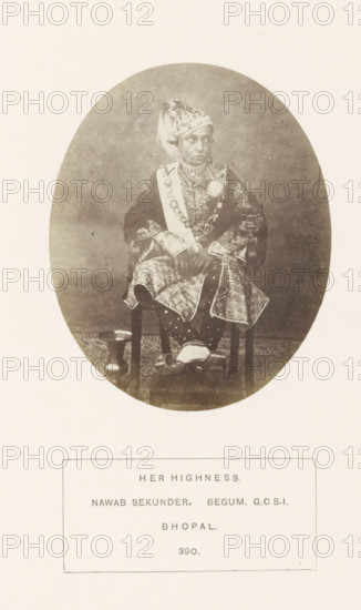 Portrait of Sekunder Begum, a queen of Bhopal, Madhya Pradesh, India, photograph, page, number: '390.', inscription: 'HER HIGHNESS., NAWAB SEKUNDER, BEGUM GCSI, BHOPAL.', photographer: James John Waterhouse (possibly), Bhopal, 1862-11, Central India, paper, albumen print, height 106 mm x width 86 mm, ruler, sovereign - BB - female ruler, human races, peoples, nationalities, An oval sepia photograph shows a seated person wearing ornate traditional clothing and jewelry, including a patterned headwrap, layered necklaces, a sash, and a brooch; the garment has intricate embroidered or patterned fabric and decorative cuffs, and the person sits with hands clasped over the lap, feet resting on a small footstool while a rounded vessel is visible on the floor beside the chair.
