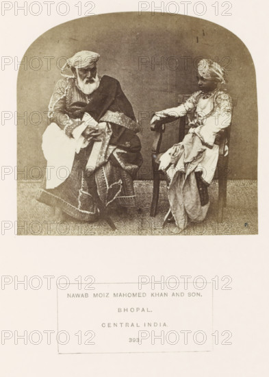 Portrait of Moiz Mahomed Khan, an officer at Sekunder Begum, a queen of Bhopal, and his son, Bhopal, Madhya Pradesh, India, photograph, page, inscription: 'NAWAB MOIZ MAHOMED KHAN AND SON., BHOPAL., CENTRAL INDIA.', number: '393.', photographer: James John Waterhouse (possibly), 1862, Central India, paper, albumen print, height 111 mm x width 119 mm, ruler, sovereign, human races, peoples, nationalities, An older man with a white beard and a turban sits on the left wearing layered, ornate garments with patterned borders and a draped shawl, his hands resting in his lap, while a younger boy on the right also wearing a turban and richly decorated clothing sits on a wooden chair with one arm on the chair back and fabric draped over his legs; both are positioned against a plain backdrop and a patterned floor covering is visible beneath them.